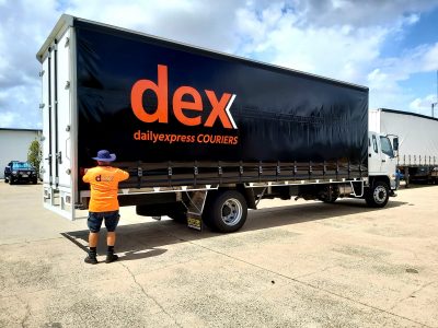 A Man Stands Next to A "dex" Truck, Smiling on A Sunny Day — Daily Express Couriers in Bowen, QLD