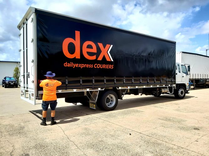 A Man Stands Next to A "dex" Truck, Smiling on A Sunny Day — Daily Express Couriers in Bowen, QLD